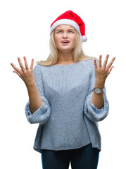 Poster - Young caucasian woman wearing christmas hat over isolated background crazy and mad shouting and yelling with aggressive expression and arms raised. Frustration concept.