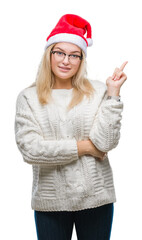 Poster - Young caucasian woman wearing christmas hat over isolated background with a big smile on face, pointing with hand and finger to the side looking at the camera.