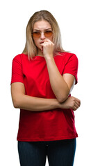 Poster - Young caucasian woman wearing sunglasses over isolated background looking stressed and nervous with hands on mouth biting nails. Anxiety problem.