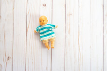 Old Plastic Mini Baby Doll Toy Wearing A Striped Sweater. Toy Is Antique From The 1980s