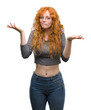 Young redhead woman clueless and confused expression with arms and hands raised. Doubt concept.