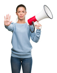 Poster - Beautiful young woman holding megaphone with open hand doing stop sign with serious and confident expression, defense gesture