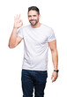© Krakenimages.com - Young man wearing casual white t-shirt over isolated background smiling positive doing ok sign with hand and fingers. Successful expression.