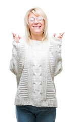 Sticker - Young beautiful blonde woman wearing winter sweater and glasses over isolated background smiling crossing fingers with hope and eyes closed. Luck and superstitious concept.