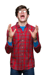 Poster - Young handsome man wearing glasses over isolated background crazy and mad shouting and yelling with aggressive expression and arms raised. Frustration concept.