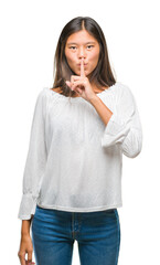 Poster - Young asian woman over isolated background asking to be quiet with finger on lips. Silence and secret concept.