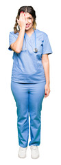 Sticker - Young adult doctor woman wearing medical uniform covering one eye with hand with confident smile on face and surprise emotion.