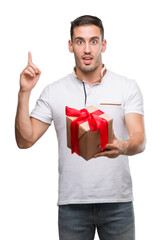 Sticker - Handsome young man giving a present surprised with an idea or question pointing finger with happy face, number one