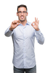 Sticker - Handsome young man holding bitcoin doing ok sign with fingers, excellent symbol