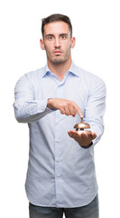 Poster - Handsome young man holding hotel ring bell with a confident expression on smart face thinking serious