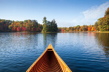 Wooden Canoe Moves On A Blue Lake With Trees In Autumn Color And A Small Island In Northern Minnesota