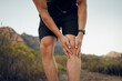© K Abrahams/peopleimages.com - Man, knee pain and injury in fitness exercise, training and health workout in nature park or countryside hiking trail. Zoom, hands and sports runner with risk emergency and medical leg accident