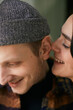 © Clique Images - Vertical close up portrait shot of young woman whispering something funny to her boyfriends ear