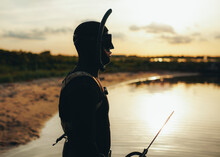 Spear Fisherman Standing In Sea Water At Sunset