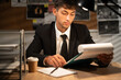 © Andrii Lysenko - Detective working at desk in his office, investigator on workplace