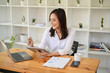 © bongkarn - Professional Asian businesswoman using laptop and tablet, working at her desk