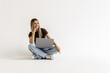 © dianagrytsku - Portrait of a woman holding laptop computer while sitting on a floor over white background