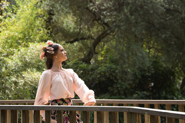 Sticker - Young teenage woman in pink shirt, black skirt with flowers and pink carnations in her hair, dancing flamenco on wooden bridge. Flamenco concept, dance, art, typical Spanish dance.