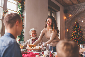 Wall Mural - Woman putting food on table for family Christmas dinner