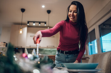 Middle aged woman decorating and setting the table for Christmas dinner