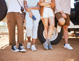 Road trip, travel and shoes with a friends outdoor by a car during summer for a holiday or vacation. Nature, fashion and stop with men and woman standing by transport while sightseeing outside