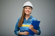 Smiling woman architect or engineer wearing safety helmet and overall holding clipboard. Isolated female portrait.