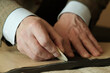 © Jevgenyij - Sewing workshop. The hands of a tailor master. Close-up. Creating patterns of clothes on fabric with a tailor's pencil.