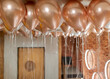 Colourful helium balloons with tails flying under ceiling decoration.