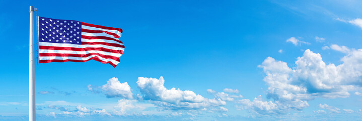 Wall Mural - USA flag waving on a blue sky in beautiful clouds - Horizontal banner
