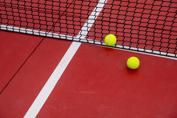 Wall Mural - two tennis balls at the net of a red court