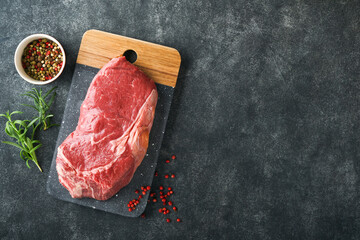 Steaks. Fresh New York Steaks raw with spices rosemary and pepper on black marble board on gray background. Top view. Mock up.