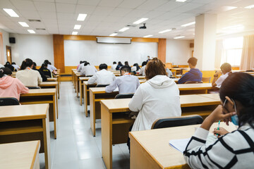 College students writing on final examination papers in the classroom concentrately