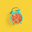 Graphics showing an alarm clock and pepperoni pizza. Time for pizza. Photo on a summer yellow background. Modern food concept. Place for text.