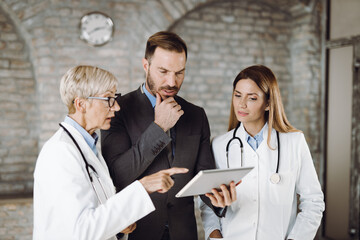 Businessman and doctors working on digital tablet in the office