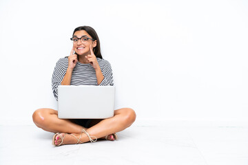 Poster - Young caucasian woman with a laptop sitting on the floor smiling with a happy and pleasant expression