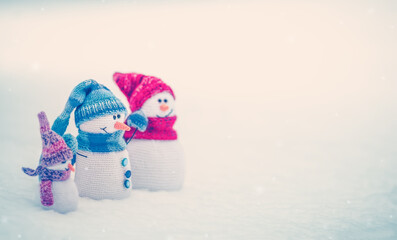 Wall Mural - Little knitted snowmen on the white snow in nature.