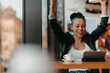 © .shock - A woman sits in a cafe with her arms raised and celebrating a job well done.Business concept