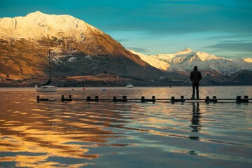 Wall Mural - Landscape view of the sunrise over the Wanaka lake surrounded by mountains. A man is standing