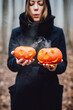 © 072Y - Woman, fashion girl in witch costume and pumpkin. Halloween decor with carved pumpkins. Halloween look, outfit. Halloween decoration with pumpkins. Pumpkin head
