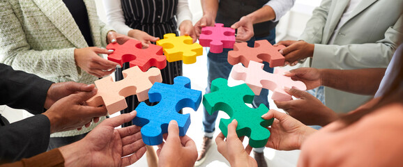 Banner background with diverse multiracial team of adult men and women who work together joining in circle colorful pieces of jigsaw puzzle. Business, education, teamwork, innovative ideas concept