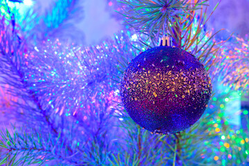 Wall Mural - The Christmas ball on a Christmas tree against the background of blurry lights from a garland.