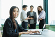 © Chaiya - young businesswoman working with latptop. woman sitting and smiling. group of young man and woman working together in relaxing workplace