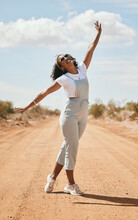 Freedom, nature and travel with a black woman on a sand road in the dessert during a summer holiday. Happy, vacation and free with an attractive young female posing outdoor with a carefree attitude