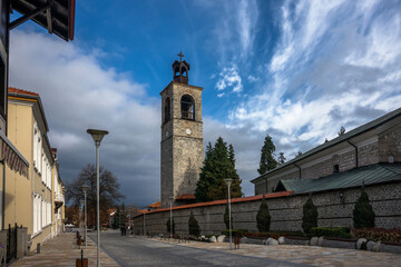 BANSKO, BULGARIA - NOVEMBER 19, 2021: Bansko city center in sunny autumn day. Holy Trinity Church and Primary School St. Paisiy Hilendarski on Pirin street.