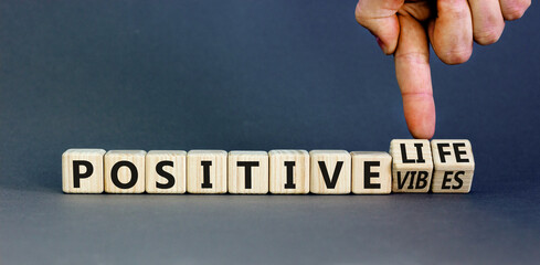 Positive vibes and life symbol. Concept words Positive vibes or Positive life on wooden cubes. Businessman hand. Beautiful grey table grey background. Business positive vibes life concept. Copy space