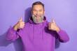 © deagreez - Photo of old age senior handsome man showing thumbs up like recommend his new hoodie clothes sale isolated on purple color background