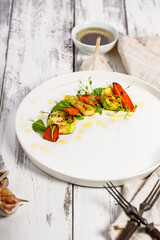 Wall Mural - Appetizing grilled vegetables on a white plate. Vegan food. Grilled zucchini and carrots with herbs and spicy sauce. Delicious and healthy food.