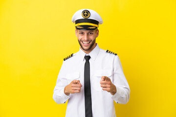 Wall Mural - Airplane caucasian pilot isolated on yellow background pointing to the front and smiling