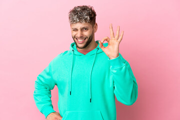 Canvas Print - Young handsome caucasian man isolated on pink background showing ok sign with fingers