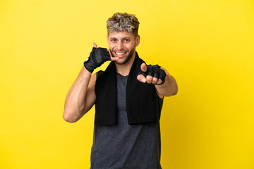 Poster - Sport caucasian man isolated on yellow background making phone gesture and pointing front